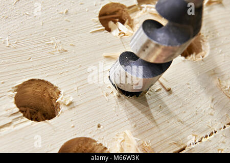 Drill for wood in the hole of the board and shavings Stock Photo