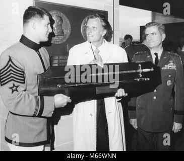 Evangelist Billy Graham (center) receives a ceremonial sword from Cadet Robert Van Antwerp (left) during ceremonies May 4, 1972 at the U.S. Military Academy at West Point, New York where Graham received the Sylvanus Thayer Award for outstanding service to the nation. At right is Lt. Gen. William A. Knowlton, superintendent of the Academy. Stock Photo