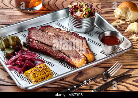 Smoked barbecue beef brisket with sauce, corn, marinated cucumber and onions Stock Photo