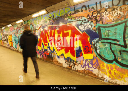 Man walks past an ANTIFA grafitti piece down a subway Stock Photo
