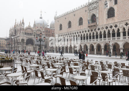 Venice, Veneto, Italy 1st March 2018. Bad weather in Venice today with sub-zero temperatures between minus 3 and minus 2 and continuous snow falling throughout the day caused by the Beast from the East, or the Siberian front from Russia sweeping across Europe.  Tourists, restaurant tables and chairs in Piazza San Marco with the Doges Palace and Basilica San Marco.