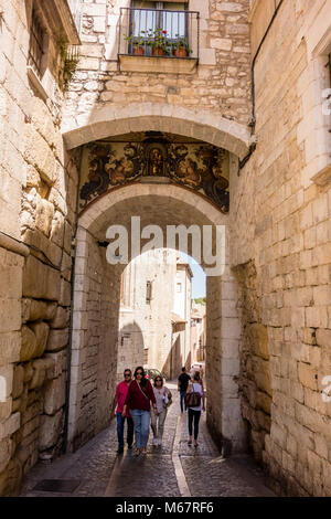 Tourists walking through passageway of medieval wall, Carrer de la Força, Girona, Catalonia, Spain Stock Photo