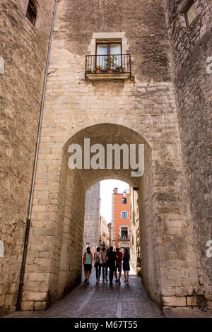 Tourists walking through passageway of medieval wall, Carrer de la Força, Girona, Catalonia, Spain Stock Photo