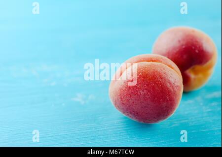 Two fresh peaches fruit on a blue wooden background Stock Photo