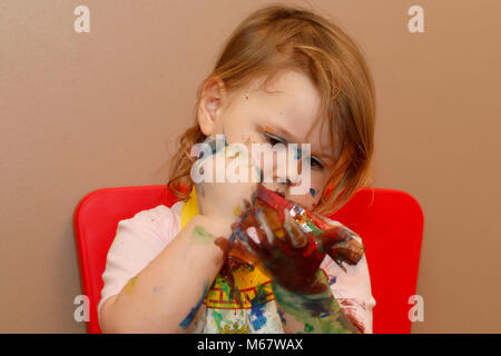 A two year old baby girl painting with water colour based paints Stock Photo