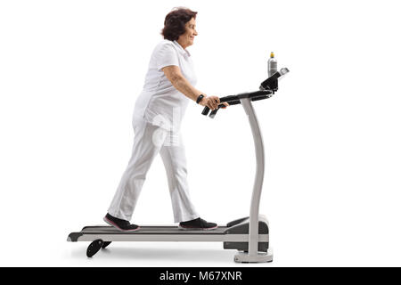 Full length profile shot of an elderly woman walking on a treadmill isolated on white background Stock Photo