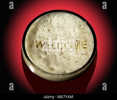 A glass of dark beer with the word 'Welcome' written in the foam, shown against a red and black graduated background Stock Photo