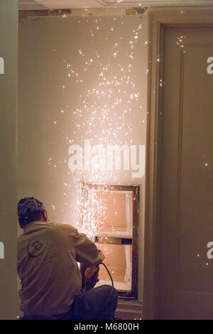Worker using steel grinder tool in apartment building hallway renovation, New York City, USA Stock Photo