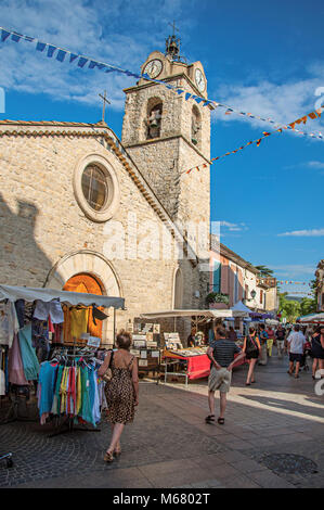 Church and stone street with stalls at sunset in lovely village of Greoux-les-Bains. Located in the Provence region, southeastern France. Stock Photo