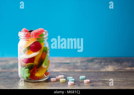 Colorful childs sweets and treats in jar on wooden table Stock Photo