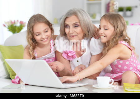 grandmother and granddaughters using laptop Stock Photo