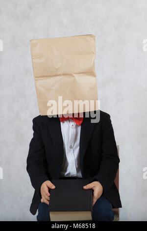 Boy of four years old with covered head is sitting on a chair. Free space for a text. Stock Photo