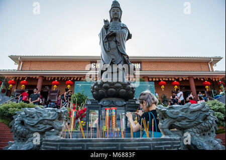 Incense offering by woman to Avalokiteshvara Boddhisattva during Lunar New Year Celebrations 2018 at Pho Minh Temple. Bankstown. AUSTRALIA Stock Photo