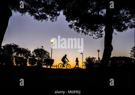 Argeles-sur-Mer (south-eastern France). Two young people riding a mountain bike and running along the waterfront in the early morning Stock Photo