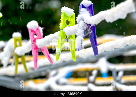 Colourful Clothes Pegs in Snow on a rotary washing line Stock Photo