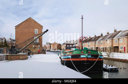 Urban scene with restored barge on canal, town houses, and minster (church) on horizon following snow storm in winter in Beverley, Yorkshire, UK. Stock Photo