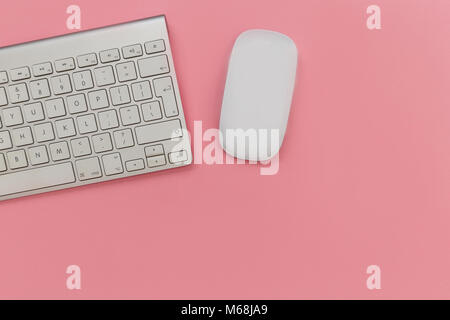 Computer keyboard and mouse overhead on pink background Stock Photo