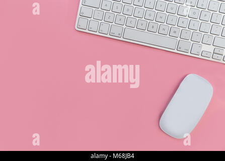 Computer keyboard and mouse overhead on pink background Stock Photo
