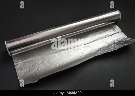 The aluminum foil used for cooking in the kitchen stands on the black floor. Stock Photo