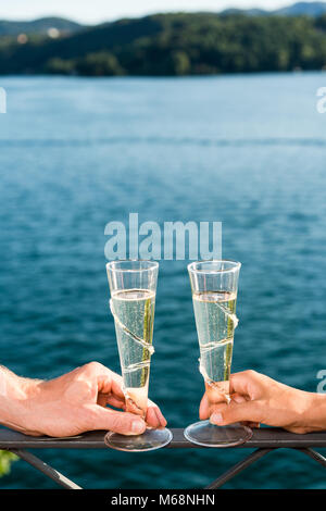 Couple holding two champagne glasses against a lake Stock Photo