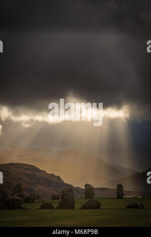 Castlerigg Stone Circle with fingers of light breaking through the stormy sky above Helvellyn in Cumbria, UK Stock Photo
