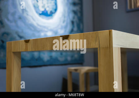 Wooden table angle made without a single nail in a room with dark purple walls and a big beautiful picture. Concept of home interior Stock Photo