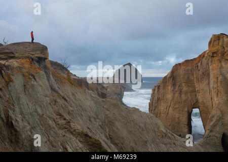 View of Cape Kiwanda with a man taking pictures on top of the cliff of stormy ocean. Taken in Pacific City, Oregon Coast, United States of America. Stock Photo