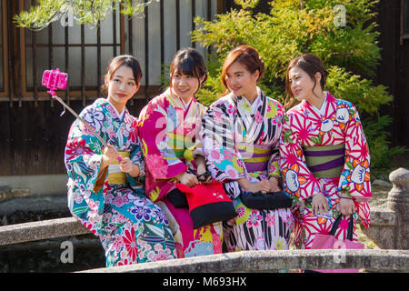 Four girls in traditional Japanese dress taking a selfie using a mobile phone in the Gion district of Kyoto, Japan. Stock Photo