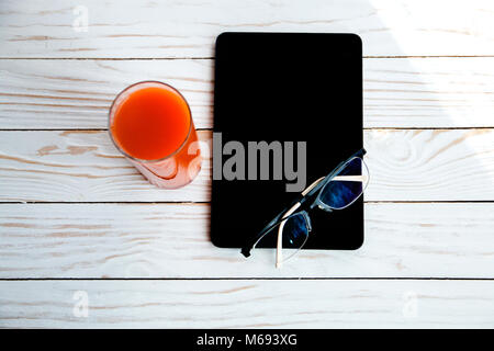 glasses on digital device on a white wooden background and juice for the rest time. Stock Photo
