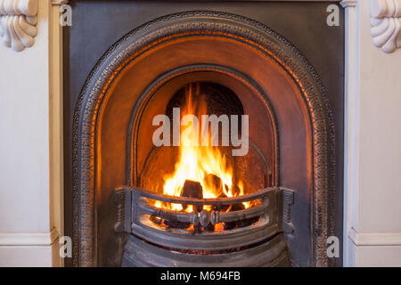 A roaring coal fire in a cast iron grate set in a marble fireplace. Stock Photo
