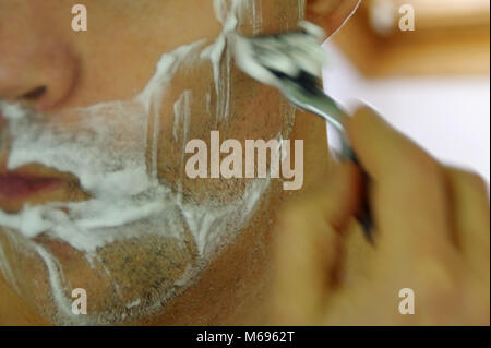 Man shaving his face using the razor. Close-up view of skin, beard and soap. Stock Photo