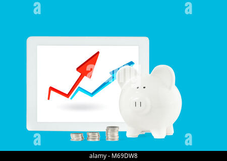 Front view. White piggy bank with coins and tablet on blue background Stock Photo