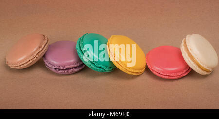 Row of bright colored macaroons on craft paper background Stock Photo