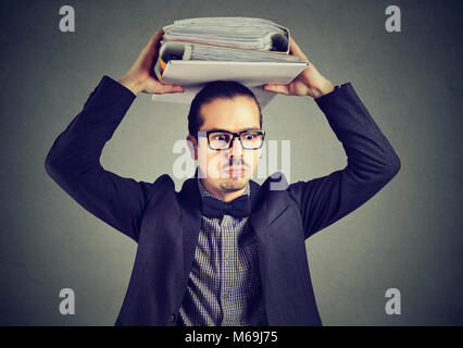 Young employee with pile of paper working in bureaucratic company with long working hours. Stock Photo
