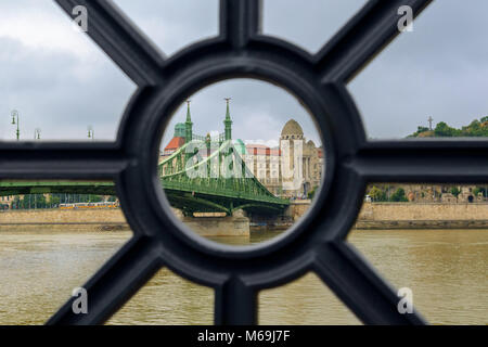 Liberty bridge and Gellert bath view throurh the hole in Danube cast iron fence Stock Photo