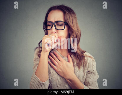 Young woman having asthma problems and coughing badly covering mouth and holding hand on chest. Stock Photo