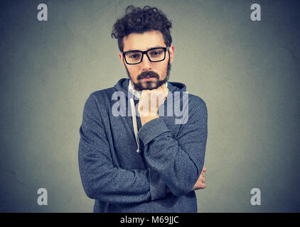 Young casual man in contemplation looking worried while looking down and solving problem in mind. Stock Photo