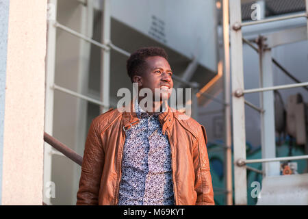 A handsome young black man in sunlight in an industrial setting Stock Photo