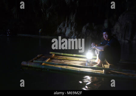 Young man with lantern on bamboo raft in cave, Tham Lod (Lod Cave), Pang Mapha, Soppong, Chiang Mai. Thailand. No mr or PR Stock Photo