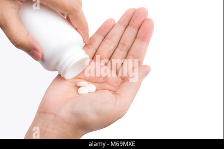 Adult woman hand pouring tablets pills out of white plastic bottle in to her hand isolated on white background. Health care in adult people Stock Photo