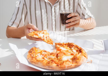 Cropped image of an asian man having lunch with pizza while working at his desk. Stock Photo