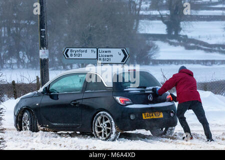 Lixwm, Flintshire, Wales, UK 2nd March 2018, UK Weather:  Storm Emma bringing stormy blizzard conditions in the uplands Flintshire with Met Office Warnings in place. Many rural areas cut off with snow ploughs and tractors attempting to clear main roads only with more snow forecasted from midday. A passer by assisting a driver to gain traction on a rural road in the vilage of Lixwm so they can return home having found the roads impassable  Flintshire, Wales  © DGDImages/Alamy Live News Stock Photo