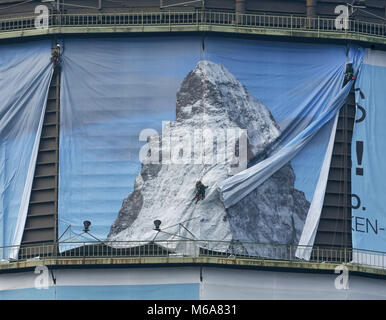 02 March 2018, Germany, Oberhausen: Industrial climbers put up a 1400 square metre big poster for the exhibition 'Der Berg ruft' (lit. the mountain calls) at the Oberhausen gasometer. The exhibition takes place from 16 March to 31 December 2018 and displays a monumental sculpture of the Matterhorn at the 100 metre high airspace of the gasometer. Photo: Roland Weihrauch/dpa Stock Photo