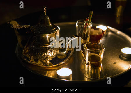 Traditional Moroccan mint tea pot and glasses served on a tray by candle light, Marrakech, Morocco Stock Photo