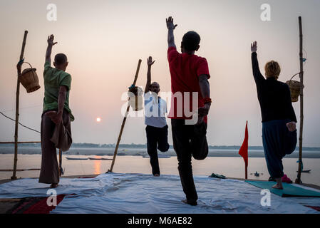 A group of people practicing yoga by the Ganges River in the early morning in Varanasi, India. 2 November 2017 Stock Photo