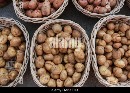 Potatoes sit in multiple wicker baskets at a local farmers market Stock Photo