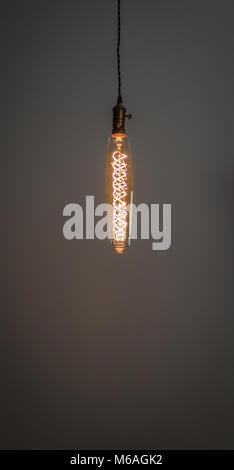 retro style Edison bulb ceiling light fixture with curly glowing filament Stock Photo