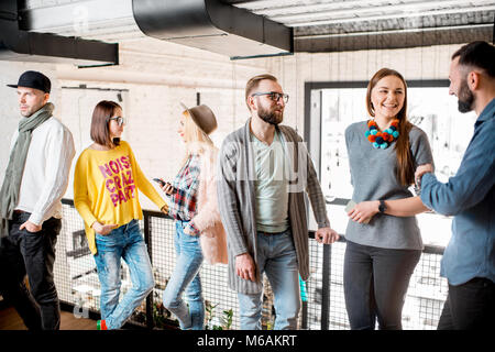 Group of friends dressed casually talking together during the coffee break standing in the white conference hall Stock Photo