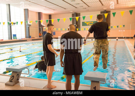 U.S. Army Spc. Jacqueline Delgado (right), assigned to the Chièvres Military Police at U.S. Army Garrison Benelux, and Army Spc. Jesse Watkins, with the Schinnen Provost Marshal Office at USAG Benelux, jump in the water with a trouser that they will use as a floatation device for the garrison’s Best Warrior Competition in the swimming pool at the Supreme Headquarters Allied Powers Europe, Belgium, Feb. 21, 2018. (U.S. Army Stock Photo