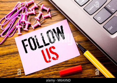 Handwritten text showing Follow Us. Business concept for Social Media Marketing written on pink sticky note paper on wooden background next to keyboar Stock Photo